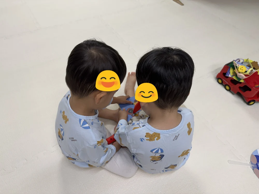 병원놀이 하는 쌍둥이 – 청진기를 든 아이와 무릎을 내민 아이
