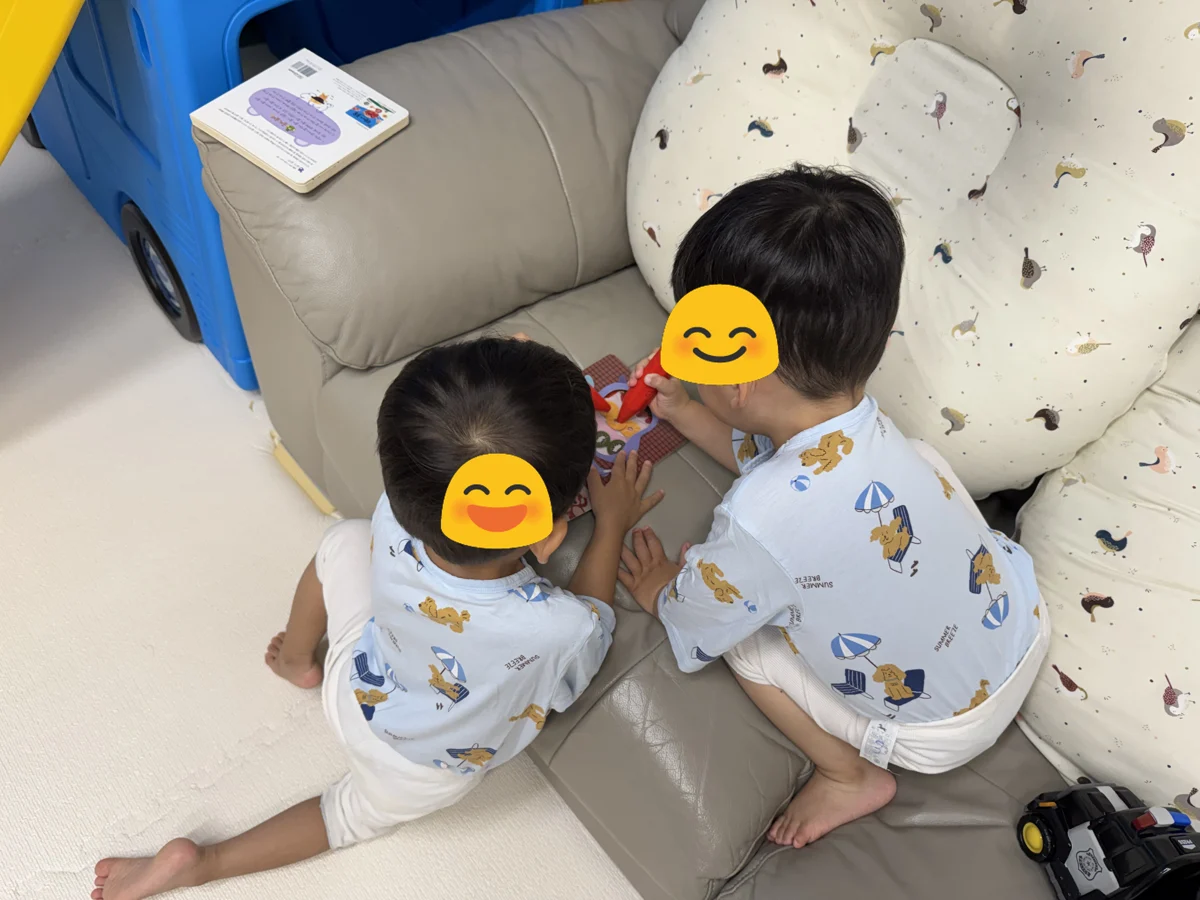 쌍둥이가 소파에서 레인온펜으로 책을 찍어보는 모습